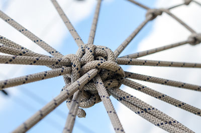 Low angle view of ropes tied on rope against sky