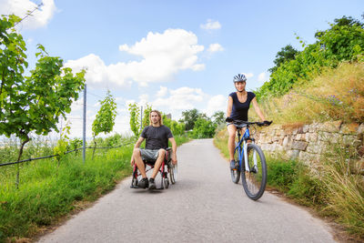 People riding bicycle on road against sky