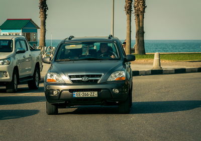 Cars parked on road by sea in city