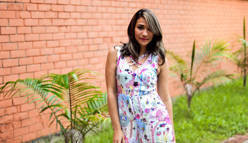 Portrait of young woman standing against wall