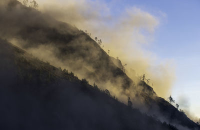 Low angle view of clouds over mountain against sky