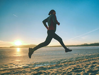 Fitness, sport people, winter season and healthy concept. man running along ice covered winter river