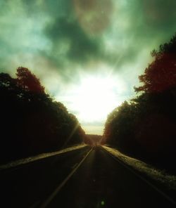 Road amidst trees against sky