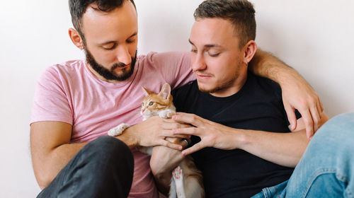 Gay couple playing with kitten.