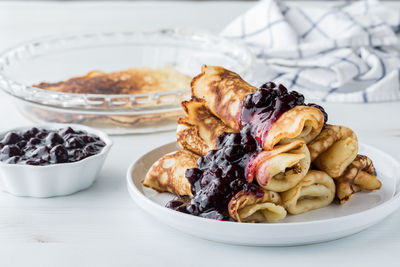 A pile of delicious rolled crepes topped with homemade blueberry sauce.