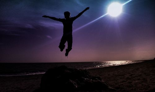 Silhouette of woman jumping on beach