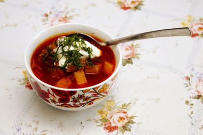 High angle view of borscht soup with spoon in bowl on table