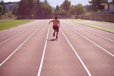 Shirtless man running on track