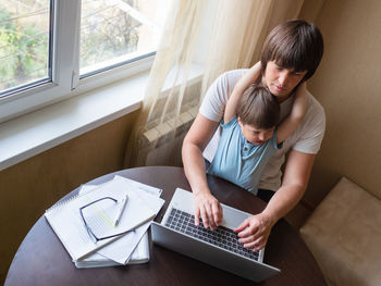 Side view of boy using laptop at home