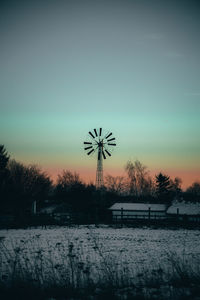Snow covered field against sky during sunset