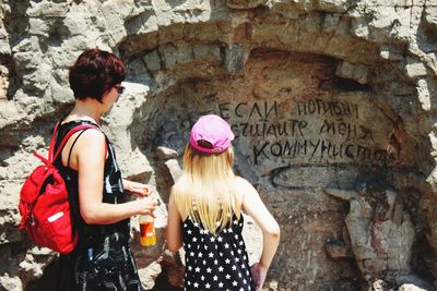 Rear view of women standing against wall