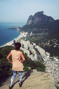 Rear view of woman standing by sea against clear sky