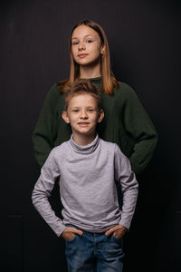 Portrait of brother and sister against black background