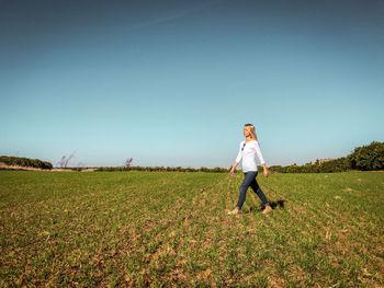 Woman walking on field against clear sky