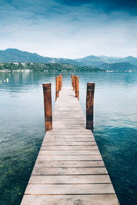 Wooden pier over lake against sky