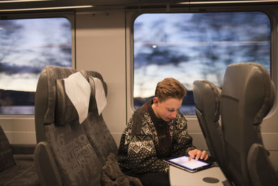 Teenage boy using tablet on train