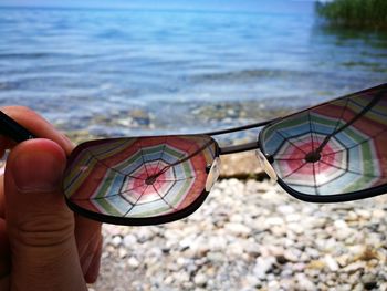 Cropped hand holding eyeglasses with reflection