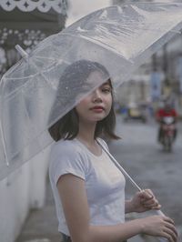 Young woman looking through wet window in rainy season