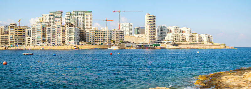 Sea by buildings against sky in city