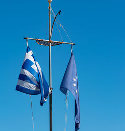 Low angle view of flags against clear blue sky