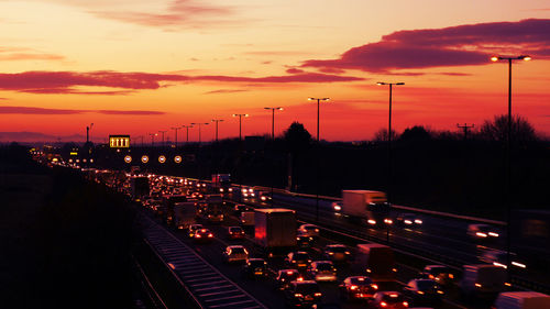 Traffic on road against dramatic sky during sunset