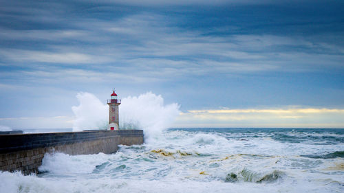 Lighthouse by sea against sky