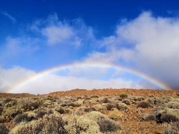 Scenic view of rainbow against sky and volcanic landscape