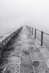 Footpath by railing against sky