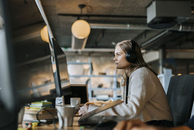 Focused young computer programmer doing coding while sitting at desk in office
