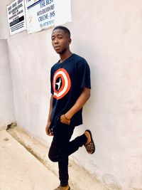 Portrait of young man standing against wall