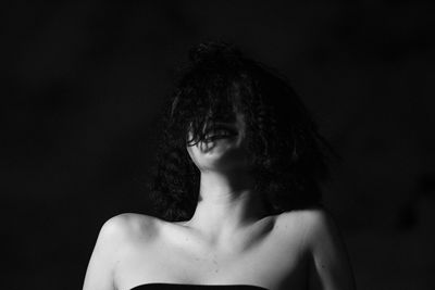 Portrait of woman looking away against black background