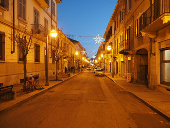 Illuminated street amidst buildings in city at night