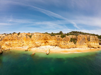 Scenic view of rock formations by sea against sky