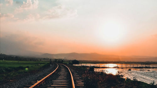 Railroad tracks against sky during sunset