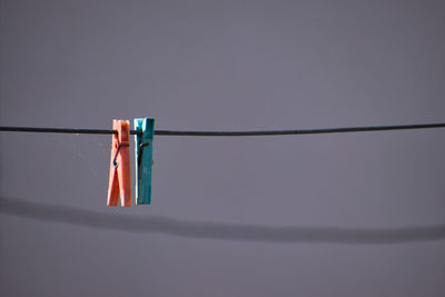 Low angle view of clothespins hanging on rope against sky