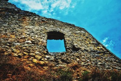 Low angle view of weathered wall against blue sky