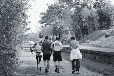 Rear view of people jogging on road