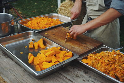 Midsection of chef cutting pumpkin on table