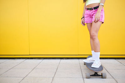 Low section of woman standing on yellow wall