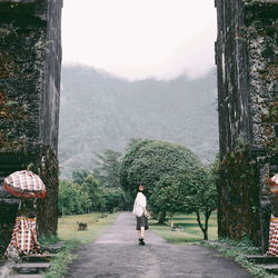 Full length of woman walking on road towards mountain