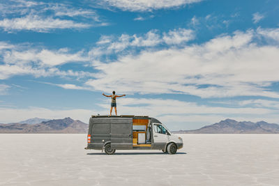 Young man standing on roof of camper van in bonneville salt flats.