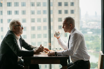 Man and coffee while sitting on table by window