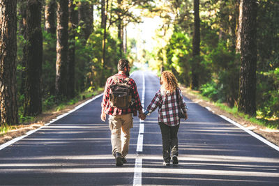 Rear view of people walking on road in forest