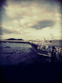 Boats in sea against cloudy sky