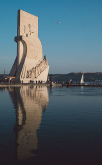 Historical building by lake against blue sky