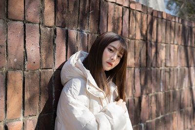 Young woman standing against wall