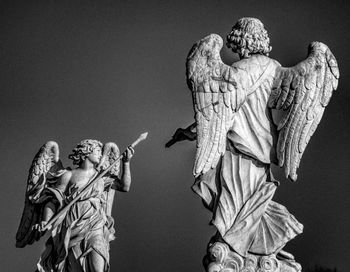 Low angle view of angel statues against clear sky