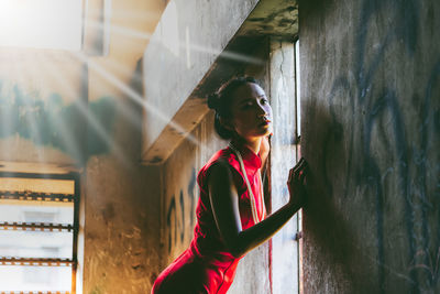 Portrait of young woman standing against wall in abandoned building