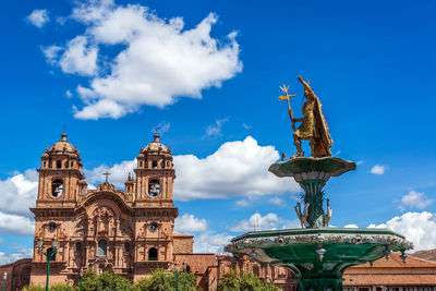 Pachacuti statue and church of the society of jesus against blue sky at plaza de armas