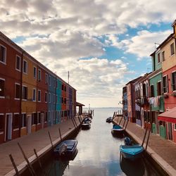 Boats moored on sea by buildings against sky in city